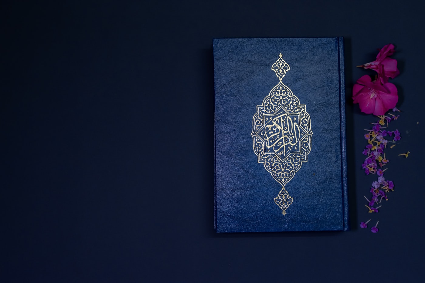 A Qur’an with an embossed cover beside flowers