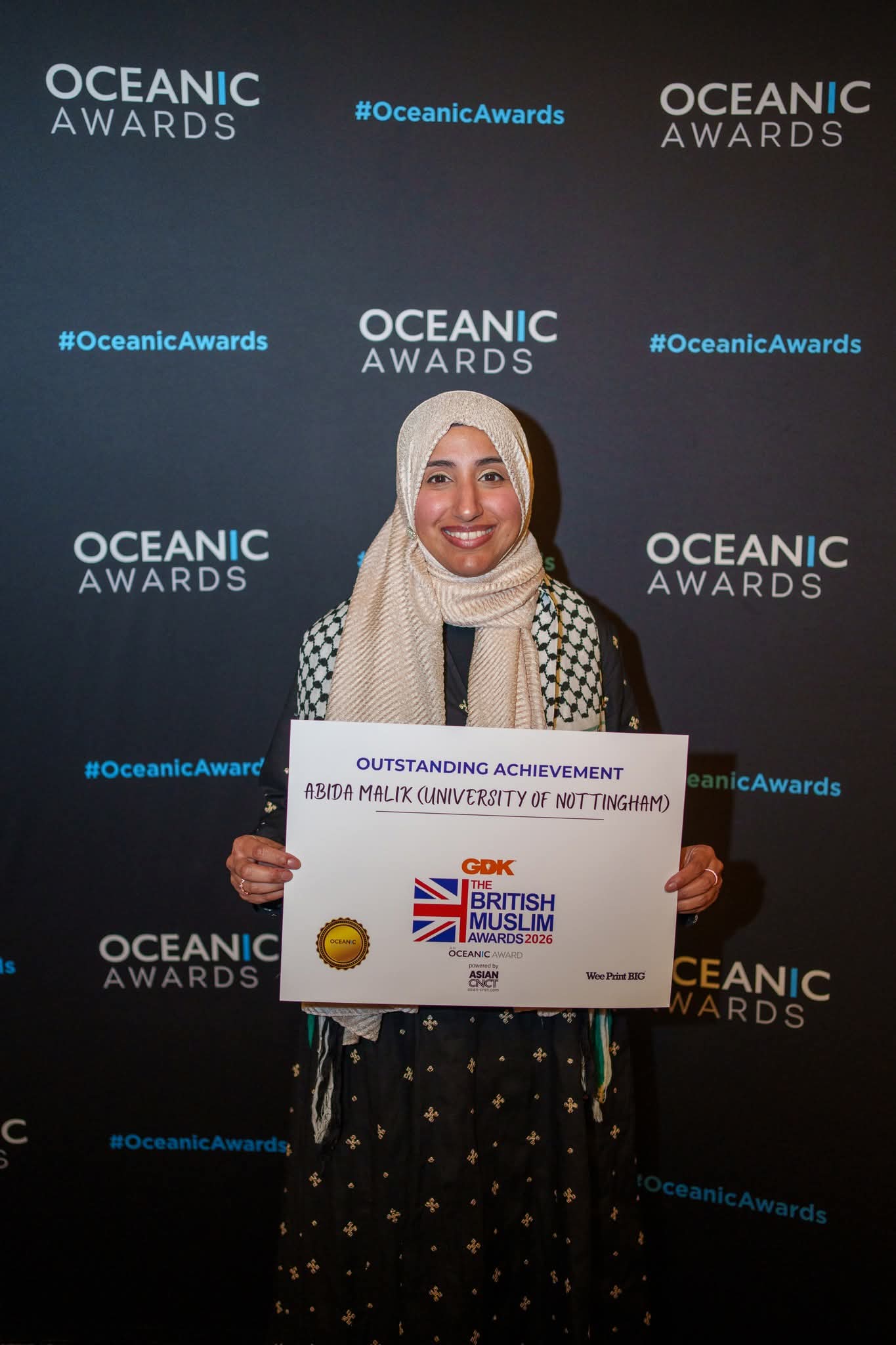 Dr Abida Malik holding an Outstanding Achievement award
