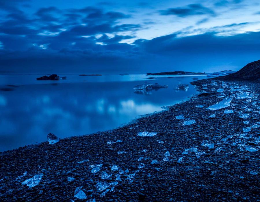 Blue-hour shoreline with ice on black sand