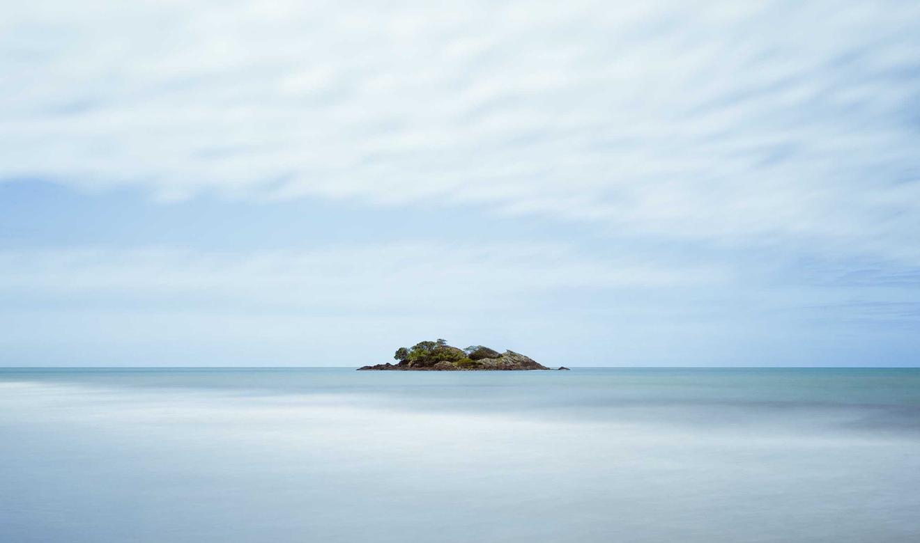 A small island on a calm, misty sea